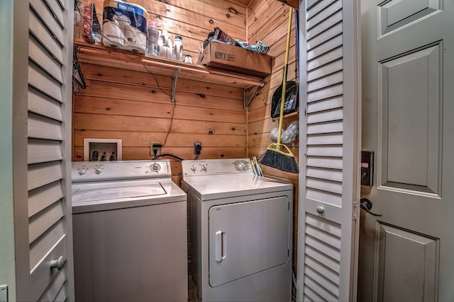 laundry room featuring laundry area, wood walls, and washing machine and clothes dryer