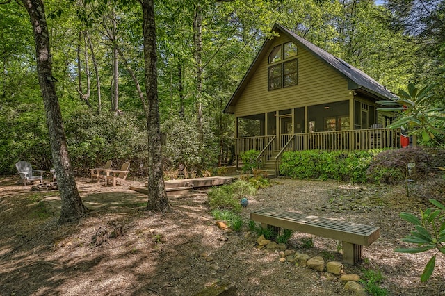 rear view of property featuring a sunroom and stairs