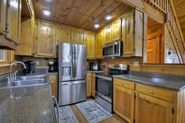 kitchen with dark countertops, appliances with stainless steel finishes, wooden ceiling, and a sink