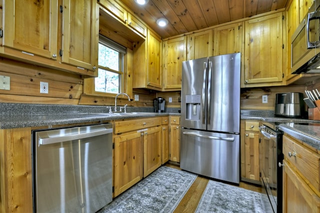 kitchen with a sink, dark countertops, wood finished floors, appliances with stainless steel finishes, and wooden ceiling