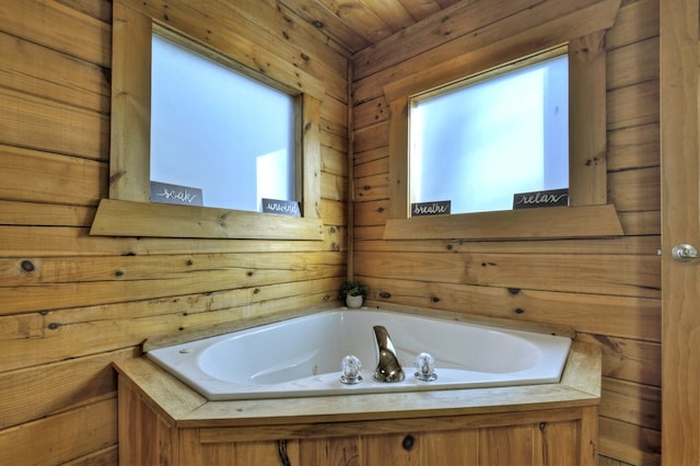 bathroom with a jetted tub and wood walls