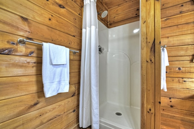 full bath featuring a shower stall and wood walls