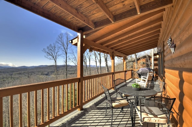 wooden deck with a mountain view, a grill, and outdoor dining space