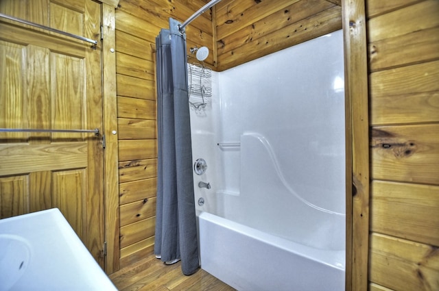 bathroom featuring wood walls, shower / bathtub combination with curtain, and wood finished floors