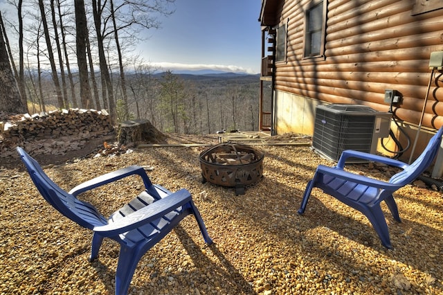 view of yard featuring a mountain view, cooling unit, an outdoor fire pit, and a view of trees