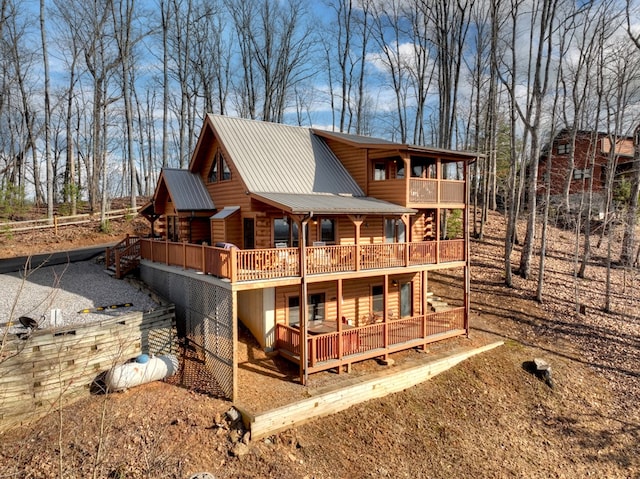 rear view of house featuring metal roof, a balcony, and a deck