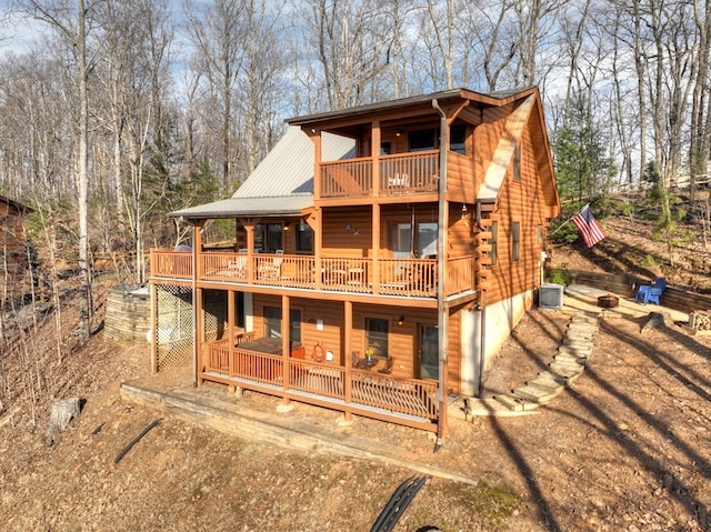 view of front facade featuring log exterior, metal roof, a deck, and dirt driveway