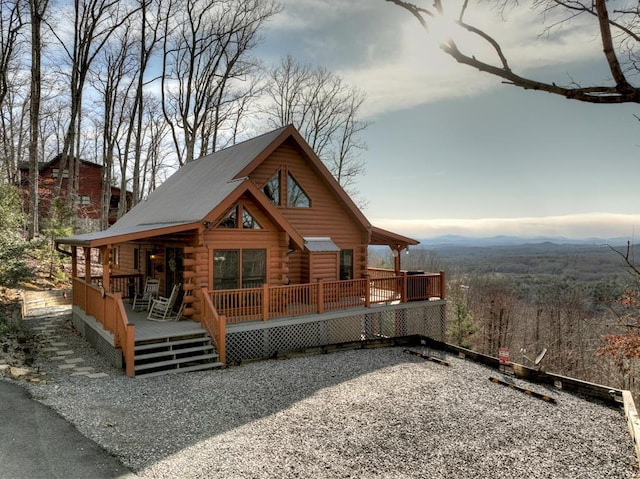 back of house featuring log siding and a deck with mountain view