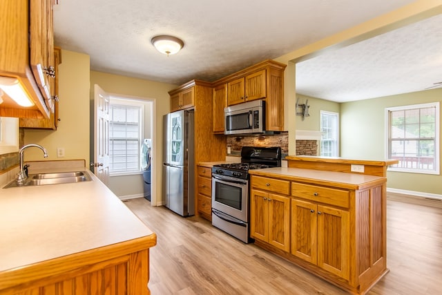 421 Burgess Rd, Ellijay, GA 30540 - kitchen featuring stainless steel appliances, a sink, a peninsula, light wood-style floors, and a textured ceiling