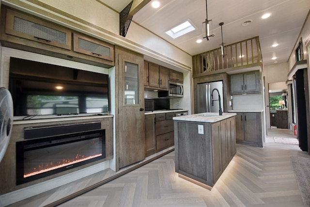 201 Kole Dr, Blairsville, GA 30512 - kitchen with appliances with stainless steel finishes, a kitchen island with sink, light countertops, a sink, and a glass covered fireplace