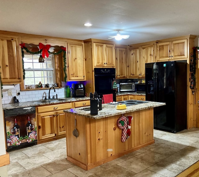 kitchen featuring sink, light stone counters, decorative backsplash, a kitchen island, and black appliances