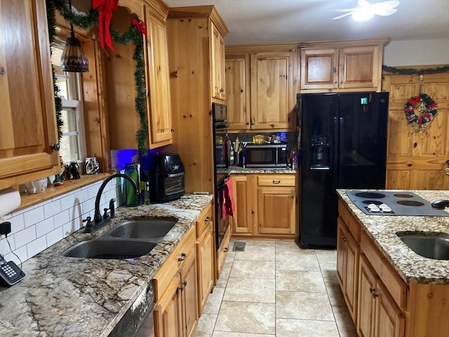 kitchen with sink, backsplash, light stone counters, and black appliances