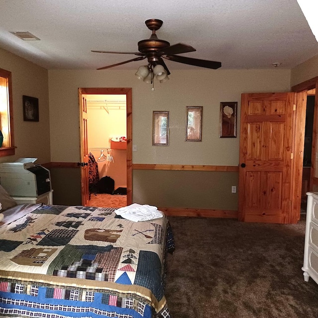 carpeted bedroom featuring a spacious closet, a closet, ceiling fan, and a textured ceiling