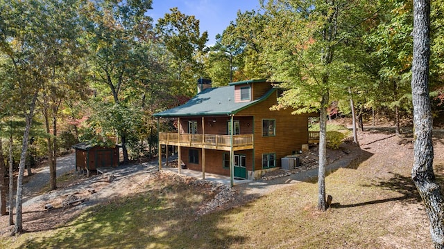 rear view of house with central air condition unit, a wooden deck, and a storage unit