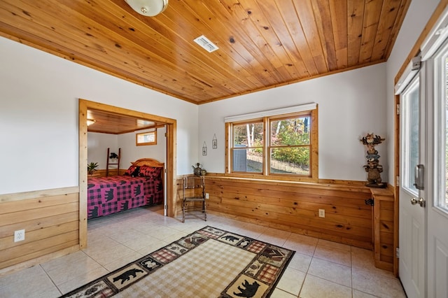 bedroom featuring wood walls, wood ceiling, light tile patterned floors, and crown molding