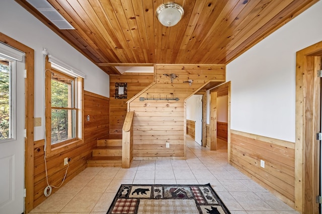 interior space with a skylight, wooden walls, wood ceiling, and light tile patterned floors