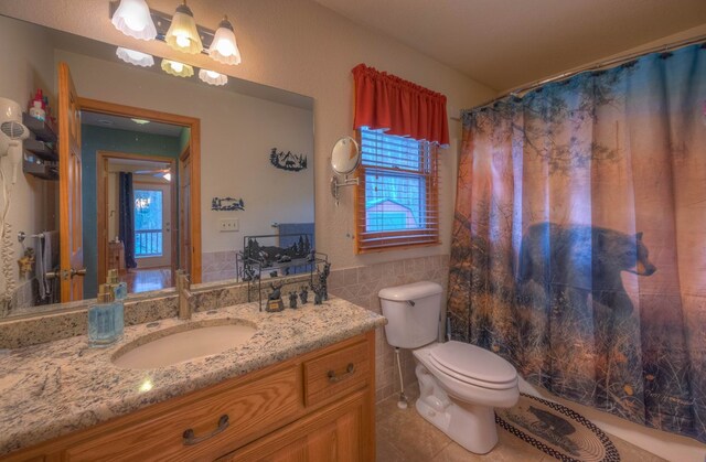 bathroom with tile walls, tile patterned flooring, vanity, and a healthy amount of sunlight