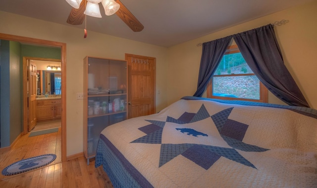 bedroom featuring light hardwood / wood-style floors, ceiling fan, and ensuite bath