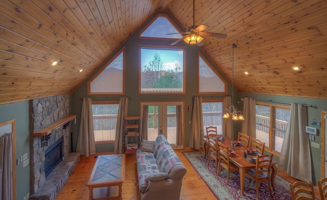 living room featuring a stone fireplace, light wood-type flooring, high vaulted ceiling, wood ceiling, and ceiling fan