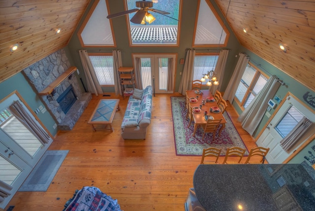 living room with french doors, a fireplace, high vaulted ceiling, hardwood / wood-style floors, and ceiling fan with notable chandelier