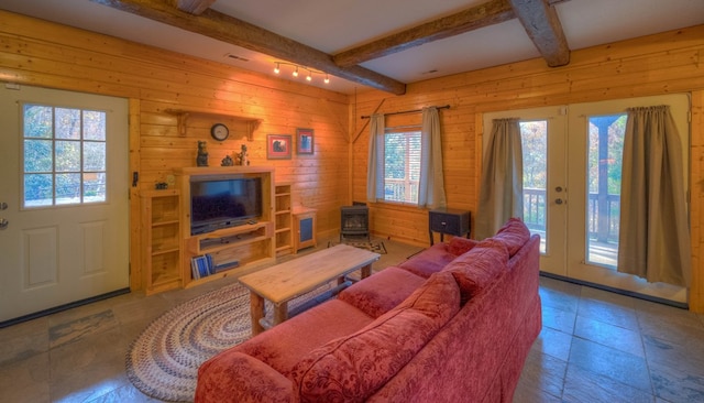 living room with beamed ceiling, a wealth of natural light, and wooden walls