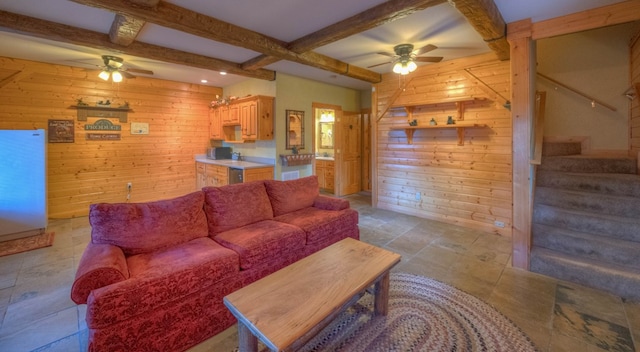 living room featuring wooden walls, ceiling fan, and beam ceiling