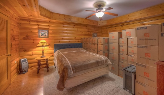 bedroom with light hardwood / wood-style flooring, ceiling fan, and log walls