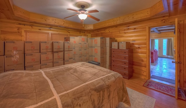 bedroom with light wood-type flooring, ceiling fan, and log walls