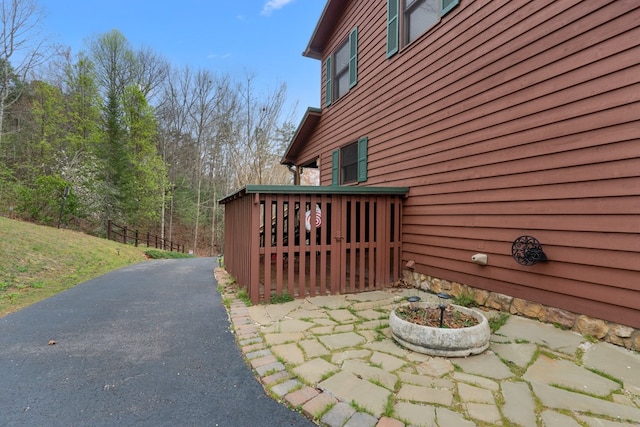 view of side of home featuring a patio and aphalt driveway