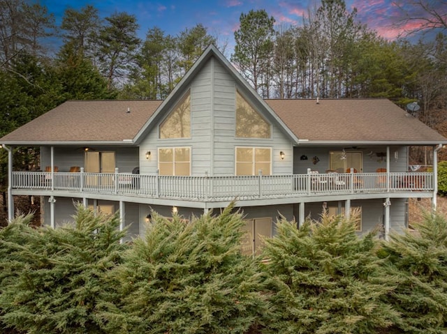 back of property at dusk with a shingled roof