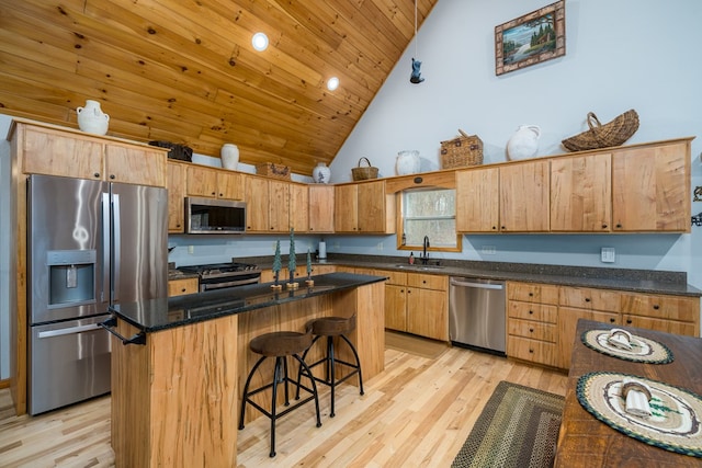 kitchen featuring stainless steel appliances, a breakfast bar, a sink, and light wood-style flooring