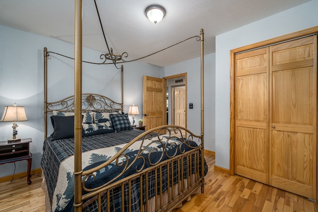 bedroom featuring light wood-style floors, a closet, a textured ceiling, and baseboards