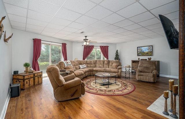 living room featuring a paneled ceiling, visible vents, baseboards, and wood finished floors