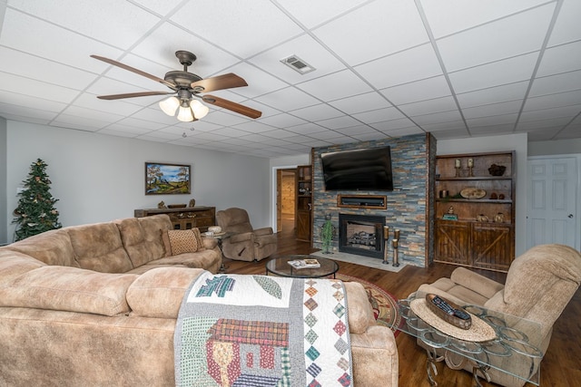 living area with visible vents, a ceiling fan, a drop ceiling, wood finished floors, and a fireplace