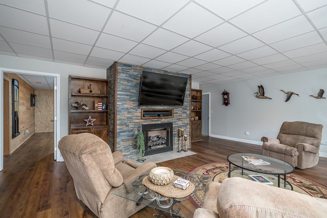 living room featuring a large fireplace, baseboards, a drop ceiling, and wood finished floors