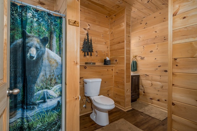 bathroom with wood walls, toilet, and wood finished floors