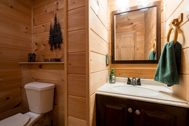 half bath with toilet, wooden walls, and vanity