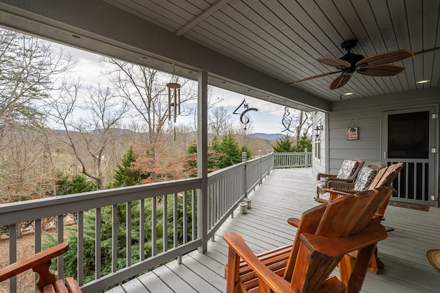 wooden deck with a mountain view and a ceiling fan