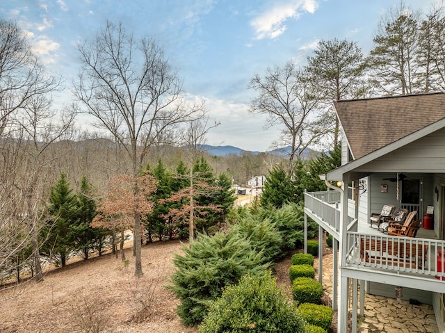 view of yard featuring a ceiling fan, a mountain view, and a balcony