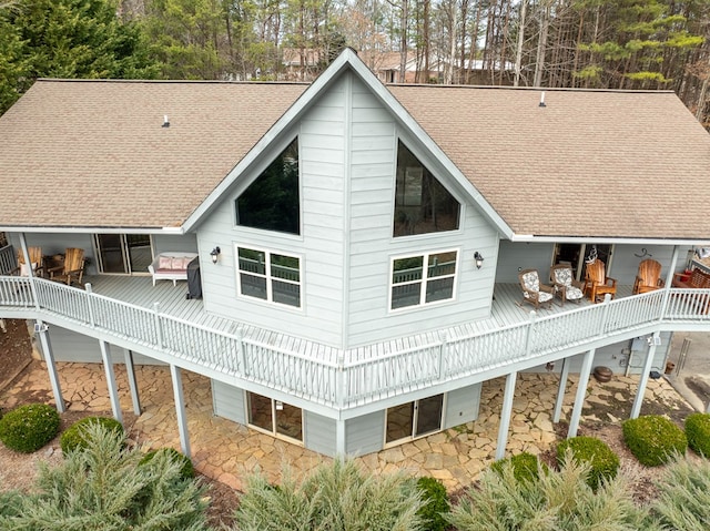 back of house with roof with shingles, a patio, and a deck