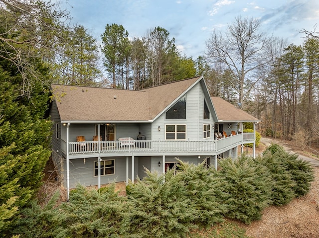 rear view of house featuring roof with shingles and a wooden deck