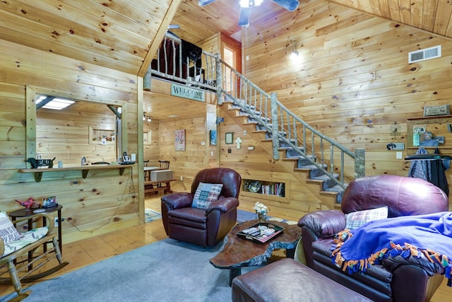 carpeted living room with wooden walls, high vaulted ceiling, wooden ceiling, and ceiling fan