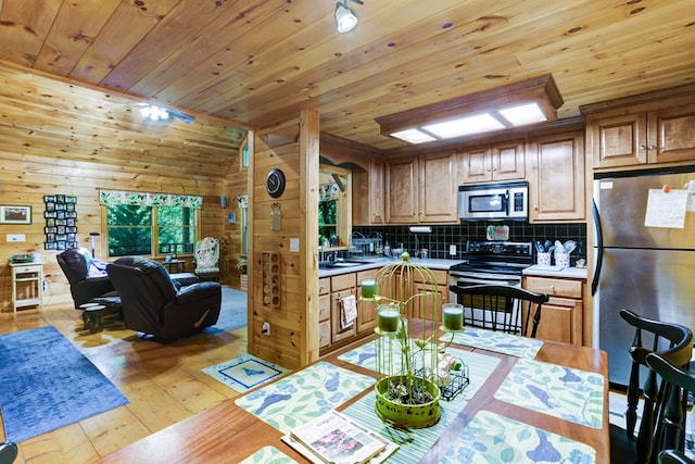 kitchen featuring wooden walls, light hardwood / wood-style flooring, vaulted ceiling, wood ceiling, and stainless steel appliances