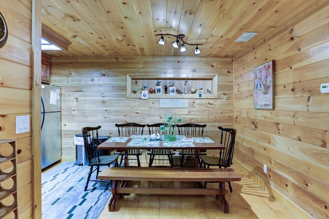 dining space featuring light hardwood / wood-style floors, wooden walls, and wood ceiling