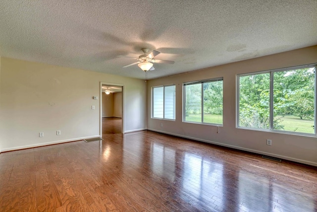 empty room featuring a textured ceiling, ceiling fan, hardwood / wood-style floors, and a healthy amount of sunlight