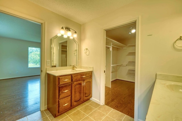 bathroom with a textured ceiling, vanity, and wood-type flooring