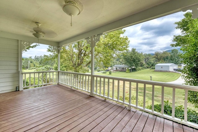 wooden deck with a lawn and ceiling fan