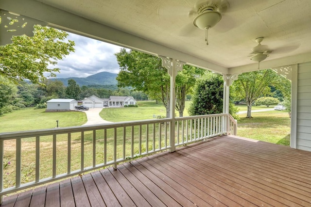 wooden terrace featuring ceiling fan, a yard, and a mountain view