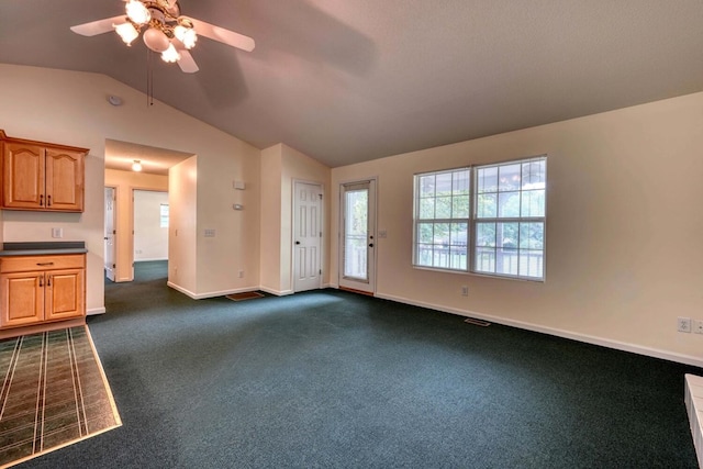 unfurnished living room with ceiling fan, dark colored carpet, and vaulted ceiling