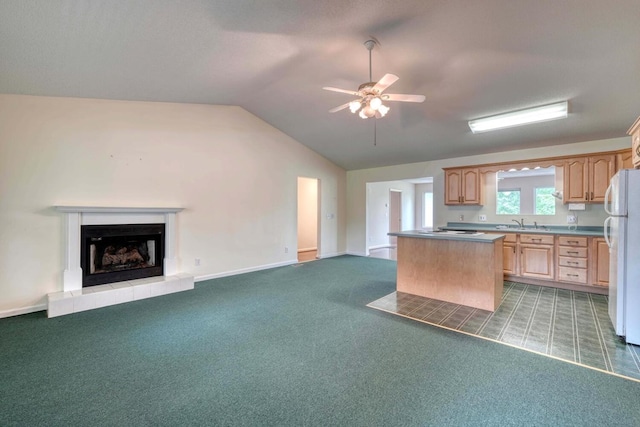 kitchen featuring carpet, light brown cabinets, a tile fireplace, vaulted ceiling, and white refrigerator